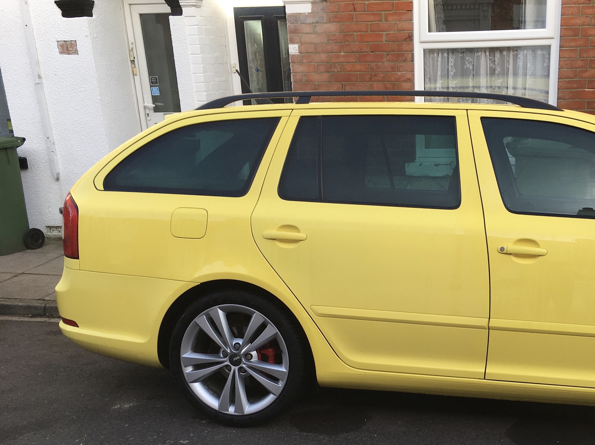 A yellow Skoda Octavia vRS estate parked on a terraced street after its body repair