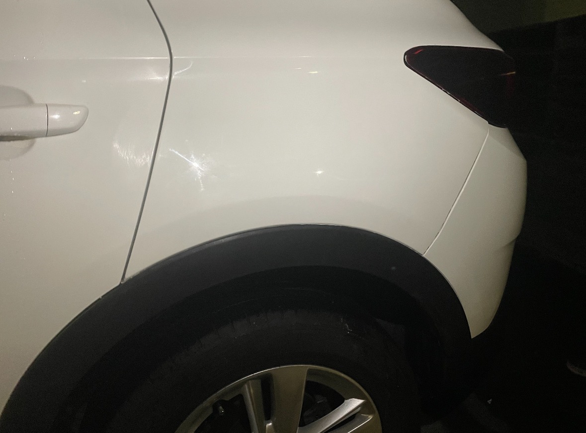 The rear quarter and wheel arch of a white SUV after its repair