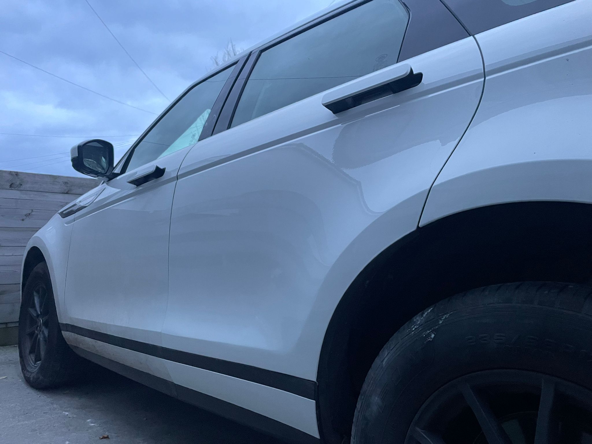 The rear door and wheel arch of a white Land Rover, smooth and glossy after repair
